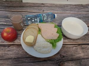 Zdjęcie przedstawia Dietę podstawową: Kakao Płatki pszenne na mleku Chleb mieszany pszenno-żytni Masło extra  Filet zapiekany drobiowy Jabłko Woda mineralna Sałata zielona Twarożek brzoskwiniowy